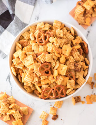 A large white bowl is filled with homemade cheddar chex mix.