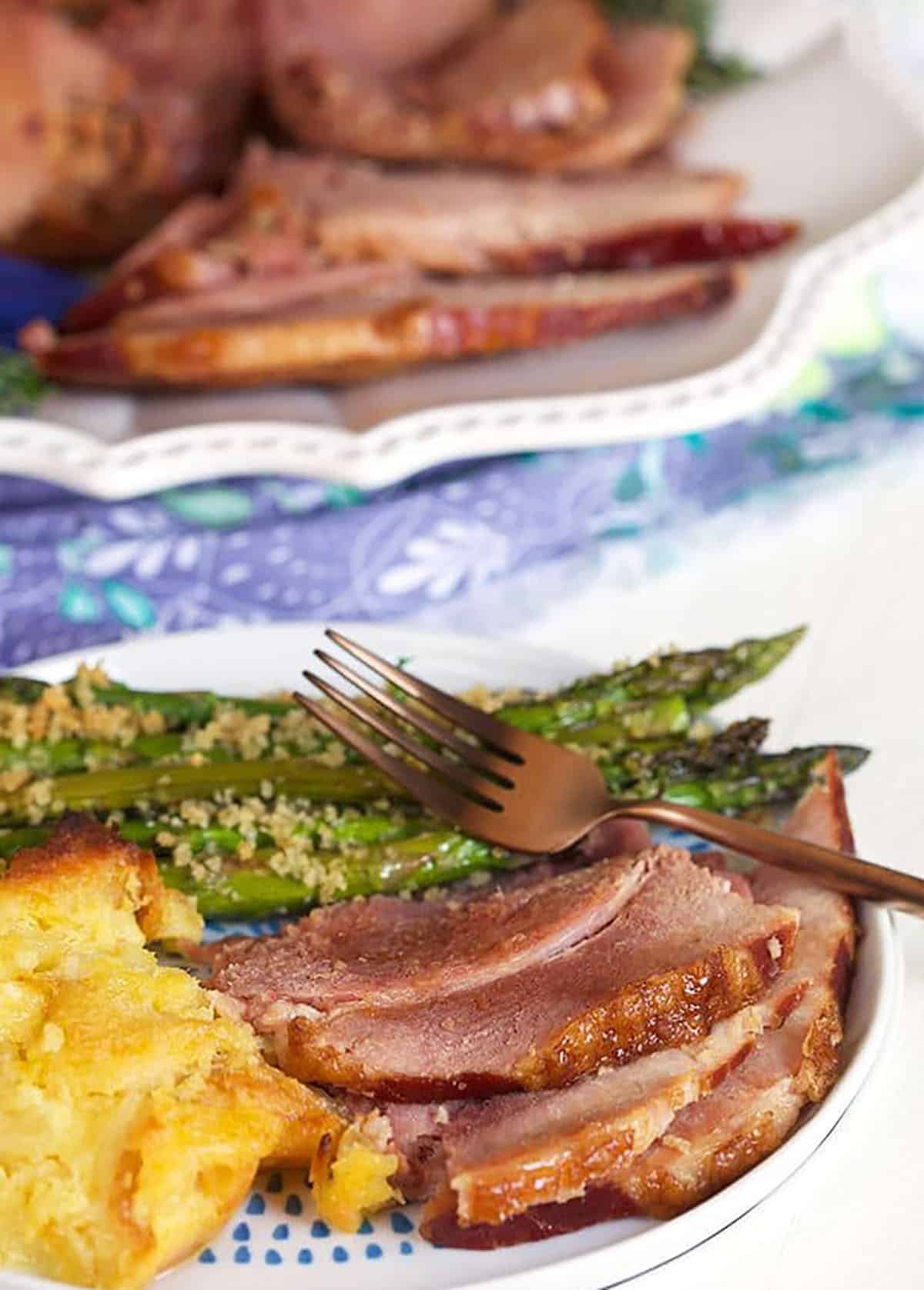ham on a plate with pineapple casserole and asparagus.