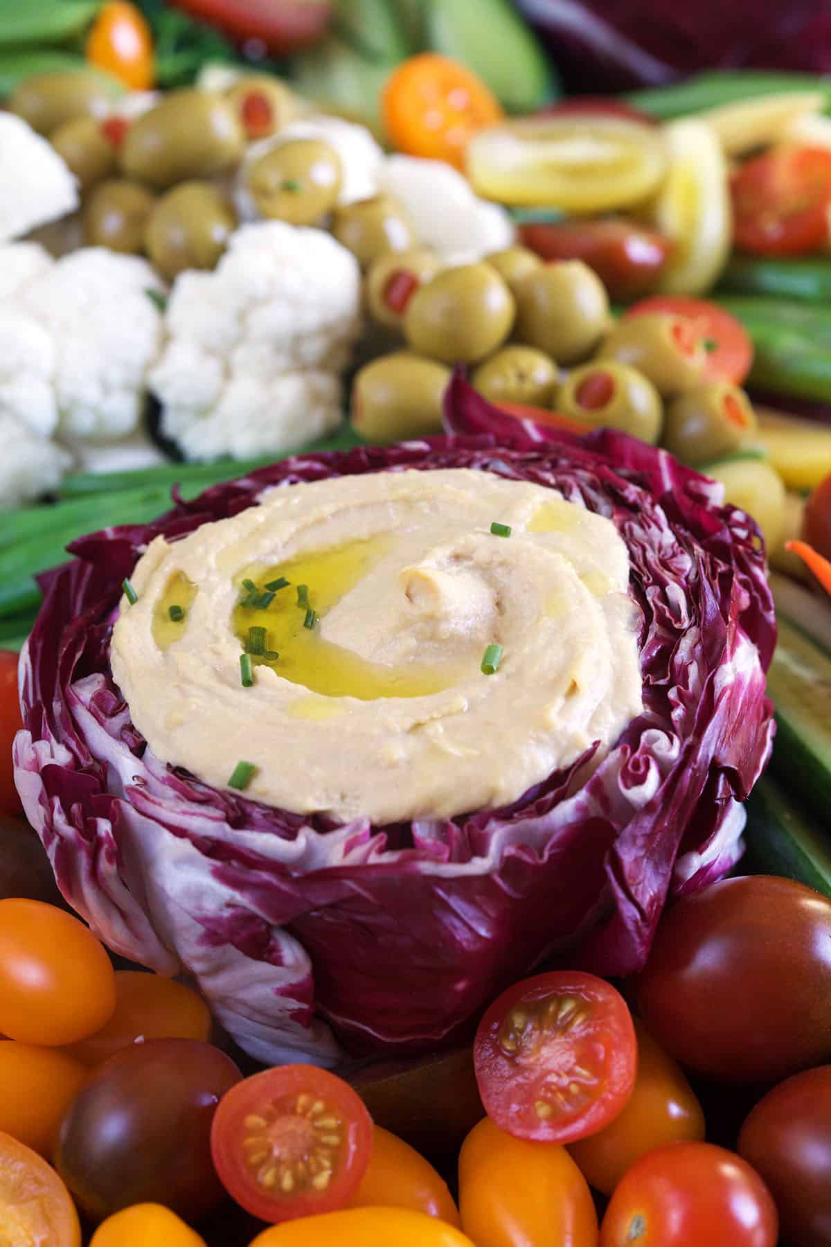 A purple head of cabbage is filled with hummus.