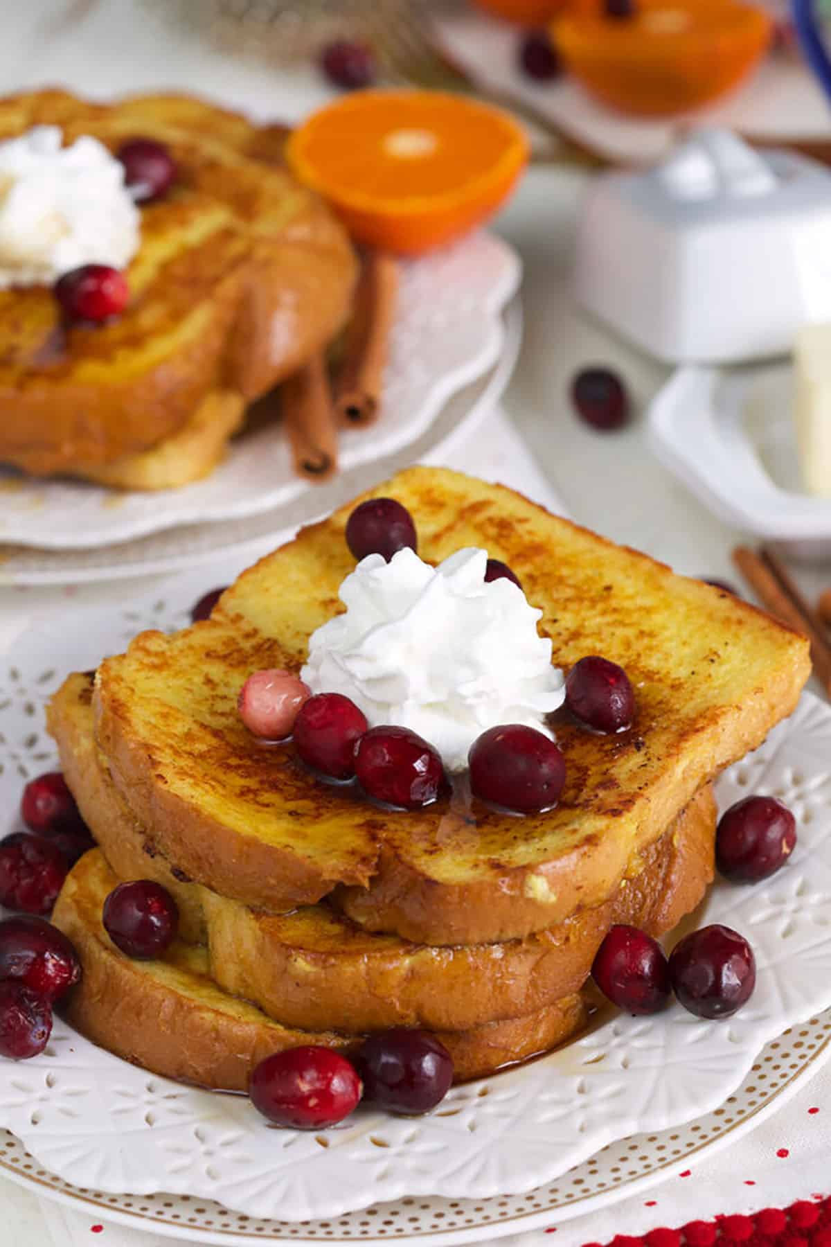 A stack of french toast is presented with cream and berries on a white plate.