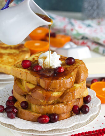 Syrup is being poured on top of a stack of eggnog french toast.