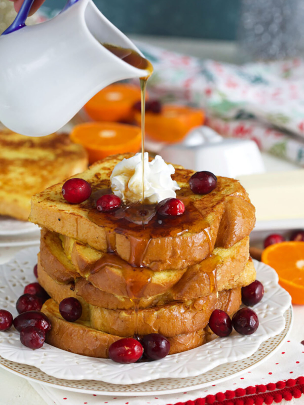 Syrup is being poured on top of a stack of eggnog french toast.
