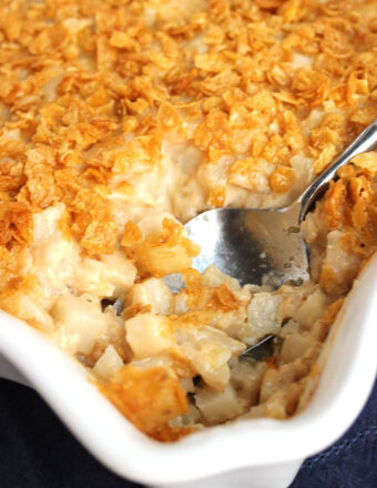 Hash Brown Casserole in a white baking dish with a spoon in for serving.