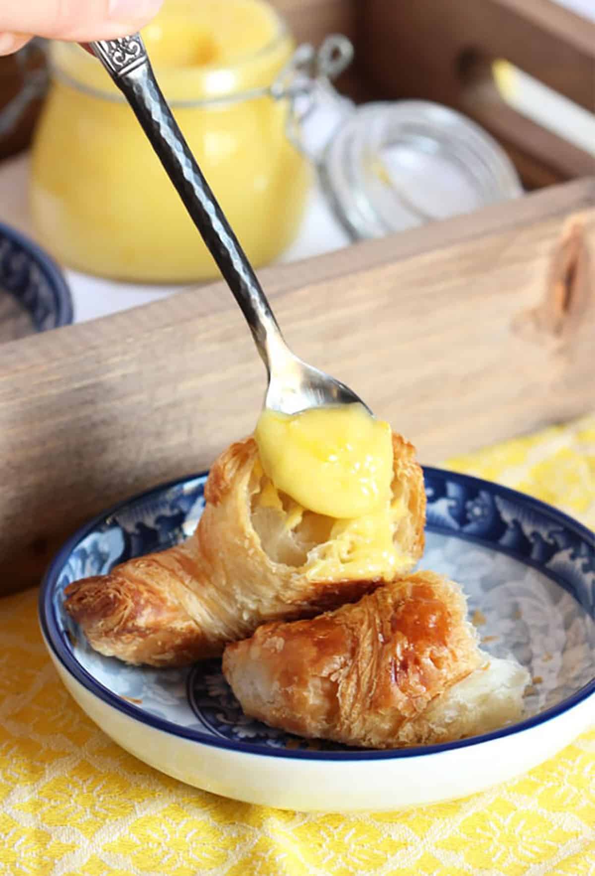 Lemon Curd being spread on a croissant.