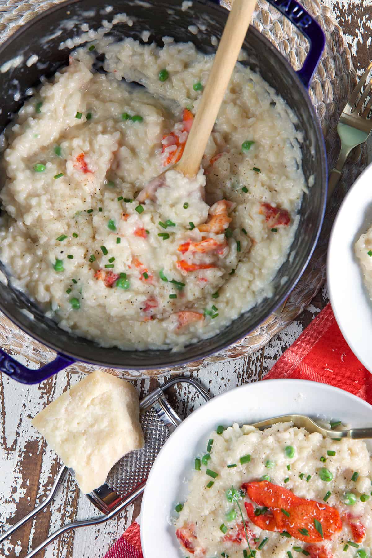 A pot is filled with lobster risotto next to a full white bowl.