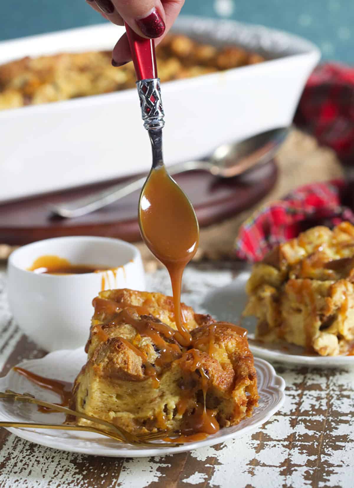 Caramel sauce is being drizzled ontop a single serving of bread pudding.