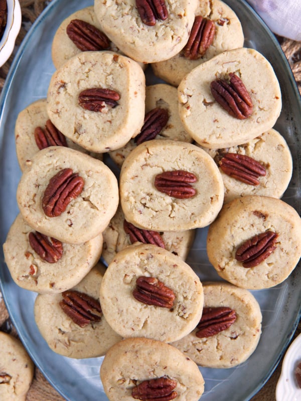 A big batch of pecan sandies are placed on an oval serving platter.