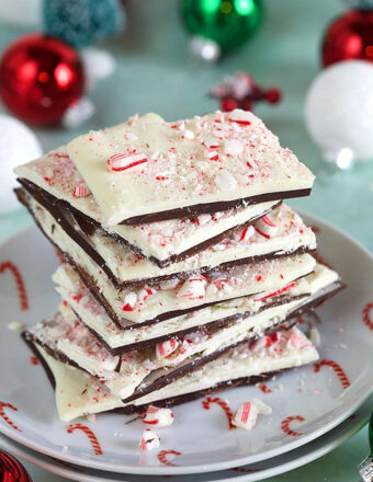 Peppermint Bark stacked on a plate with ornaments in the background.