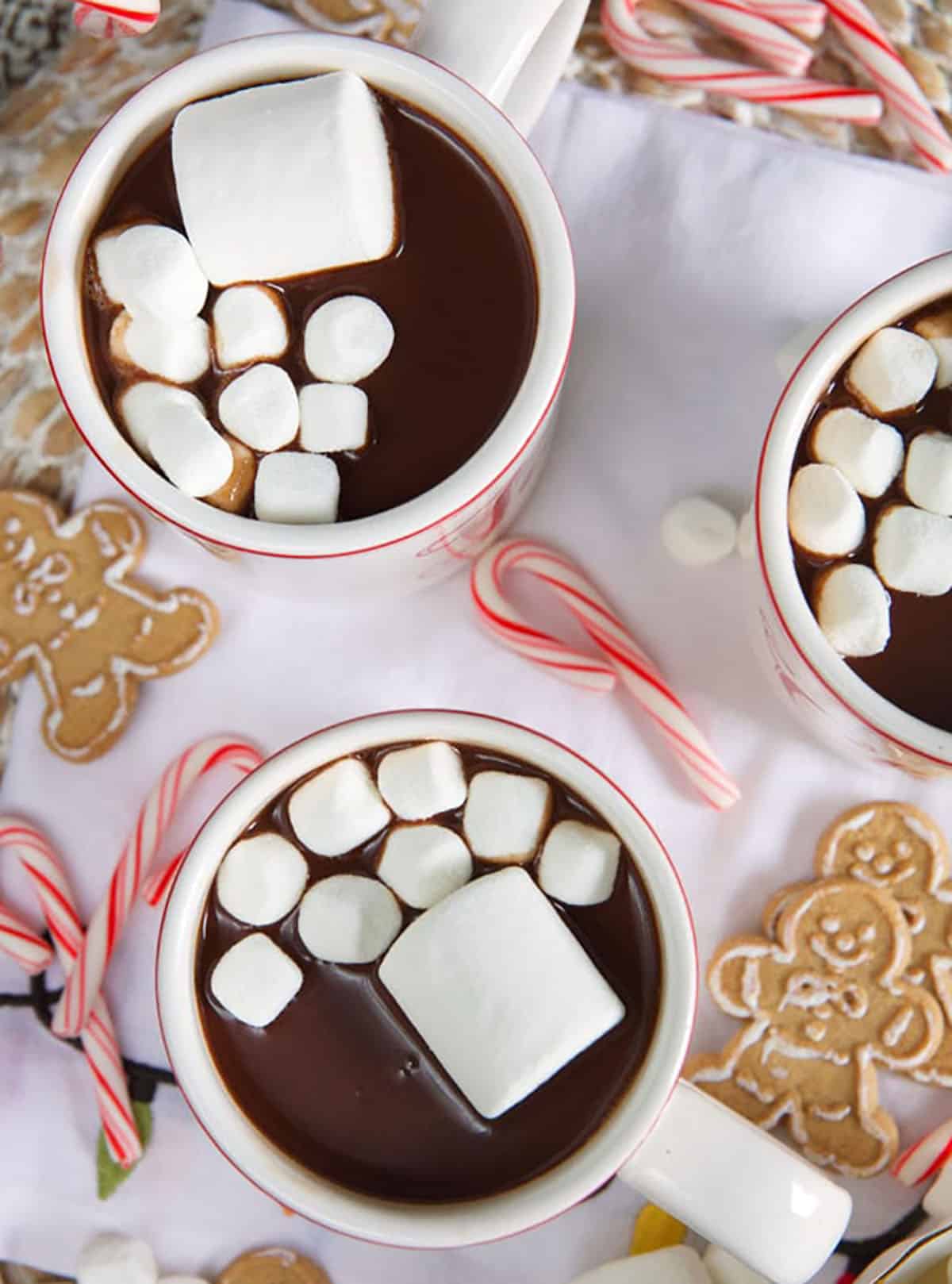 Three white mugs filled with hot chocolate are topped with marshmallows.