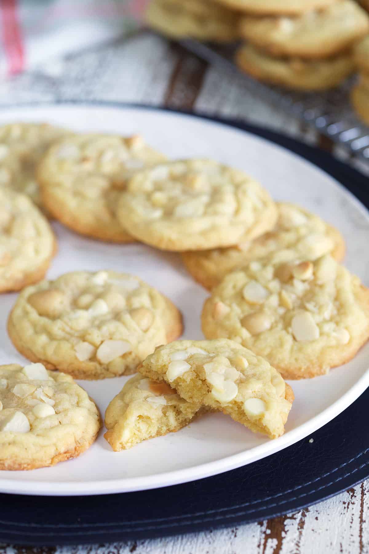 A batch of white chocolate macadamia nut cookies are presented on a white plate.