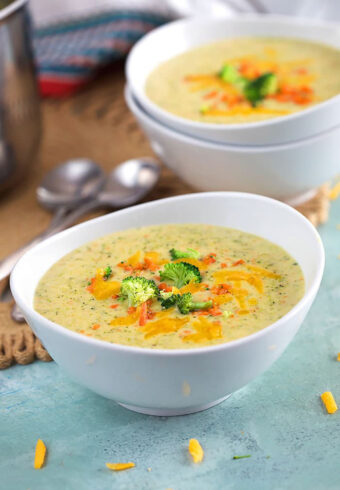 Broccoli Cheddar Soup in white bowls on a blue background.