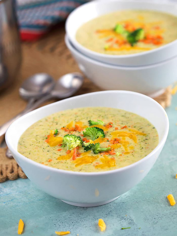 Broccoli Cheddar Soup in white bowls on a blue background.