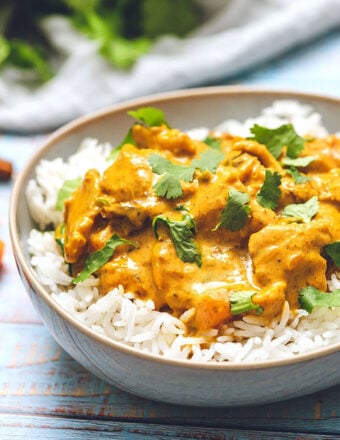 Butter Chicken in a bowl of rice with cilantro on top.