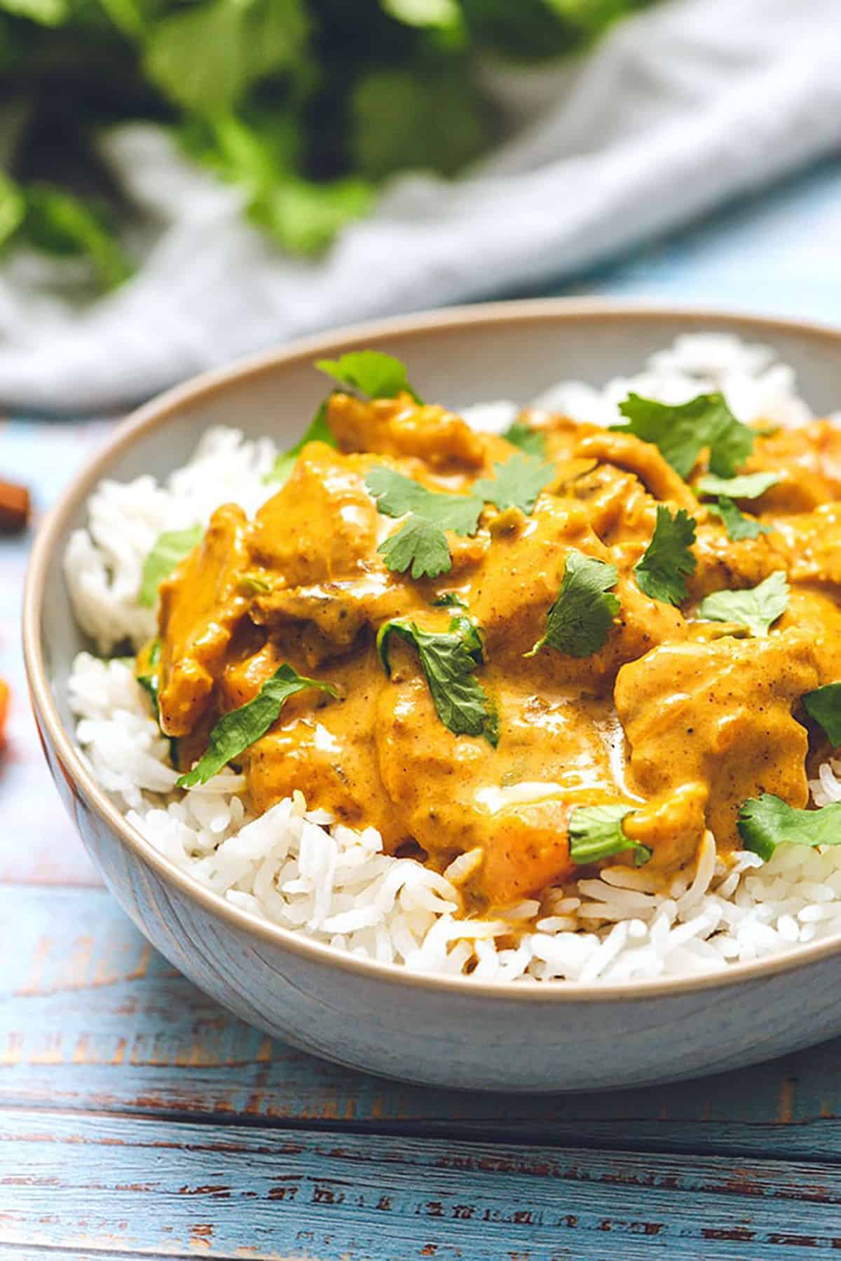 Butter Chicken in a bowl of rice with cilantro on top.