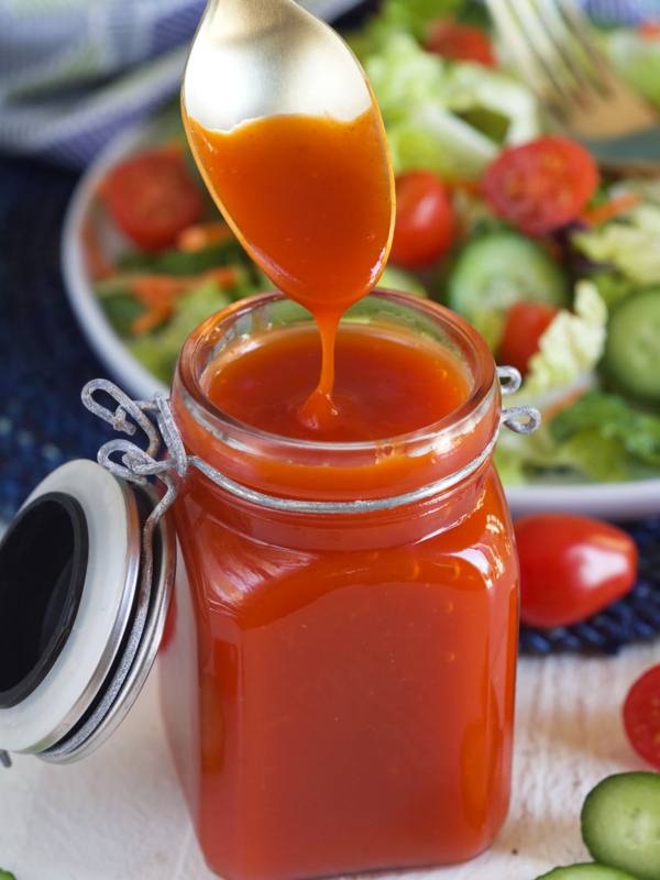 A jar of catalina dressing is being dunked into with a spoon.