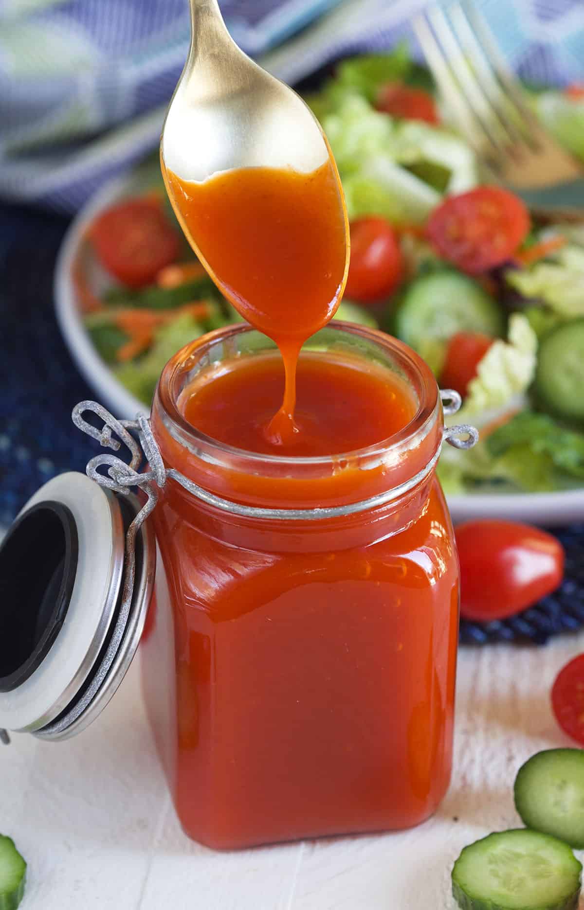 A jar of catalina dressing is being dunked into with a spoon.