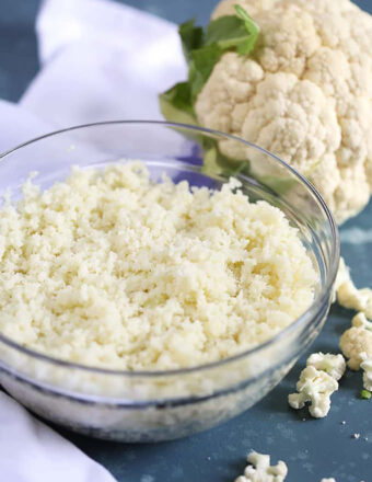 Glass bowl of cauliflower rice on a blue background