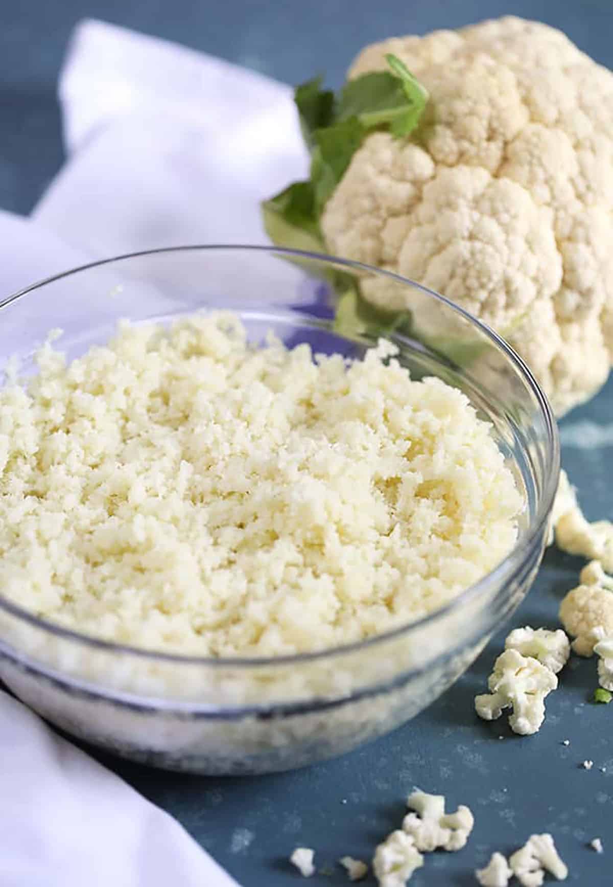 Glass bowl of cauliflower rice on a blue background 