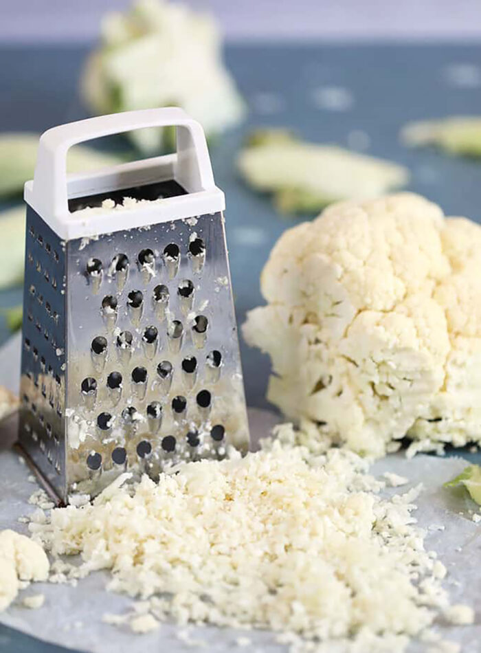 Cauliflower rice made with a box grater with a head of cauliflower