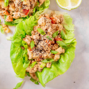Two chicken lettuce wraps are placed next to a slice of lime.