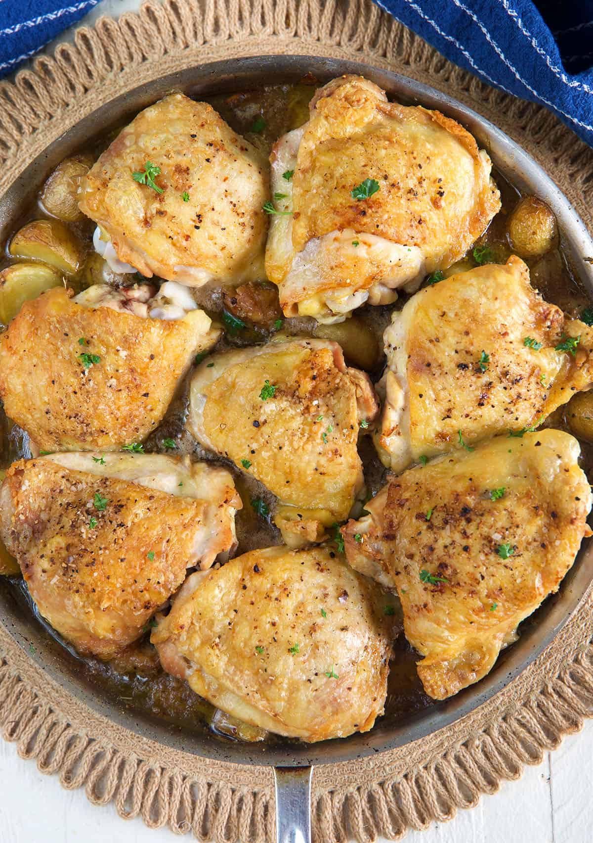 A pan of chicken thighs are being cooked in a large skillet.