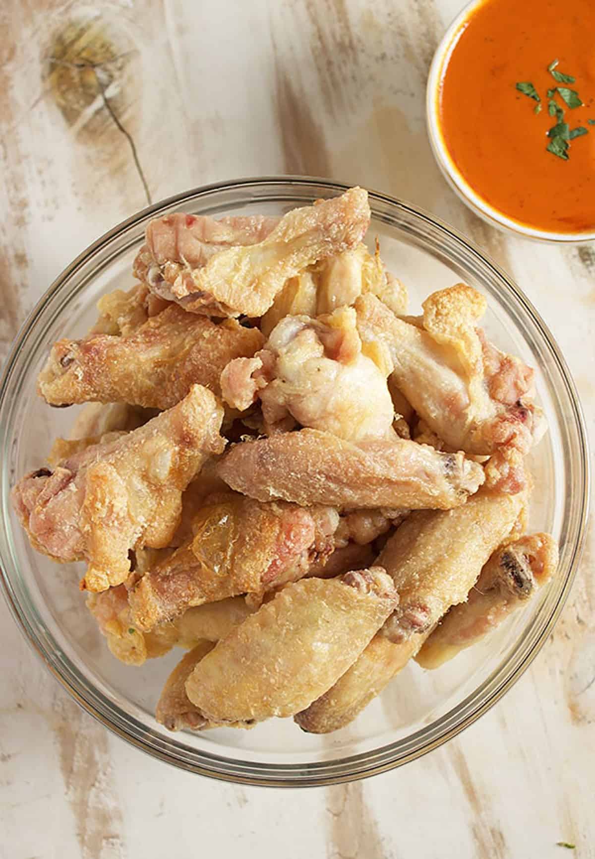 Bowl of crispy chicken wings on a wood background.