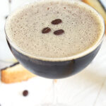 A martini glass is filled to the brim and topped with three coffee beans.