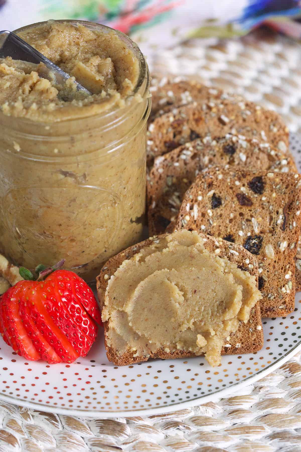 A few pieces of bread are placed around a jar filled with walnut butter.