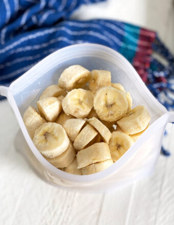 A reusable ziptop bag is open, showing a serving of sliced frozen bananas.