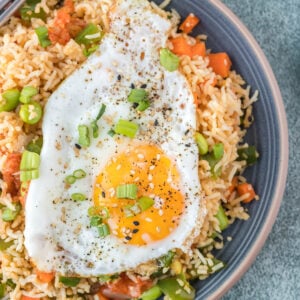 A fried egg is placed on top of a serving of kimchi fried rice.