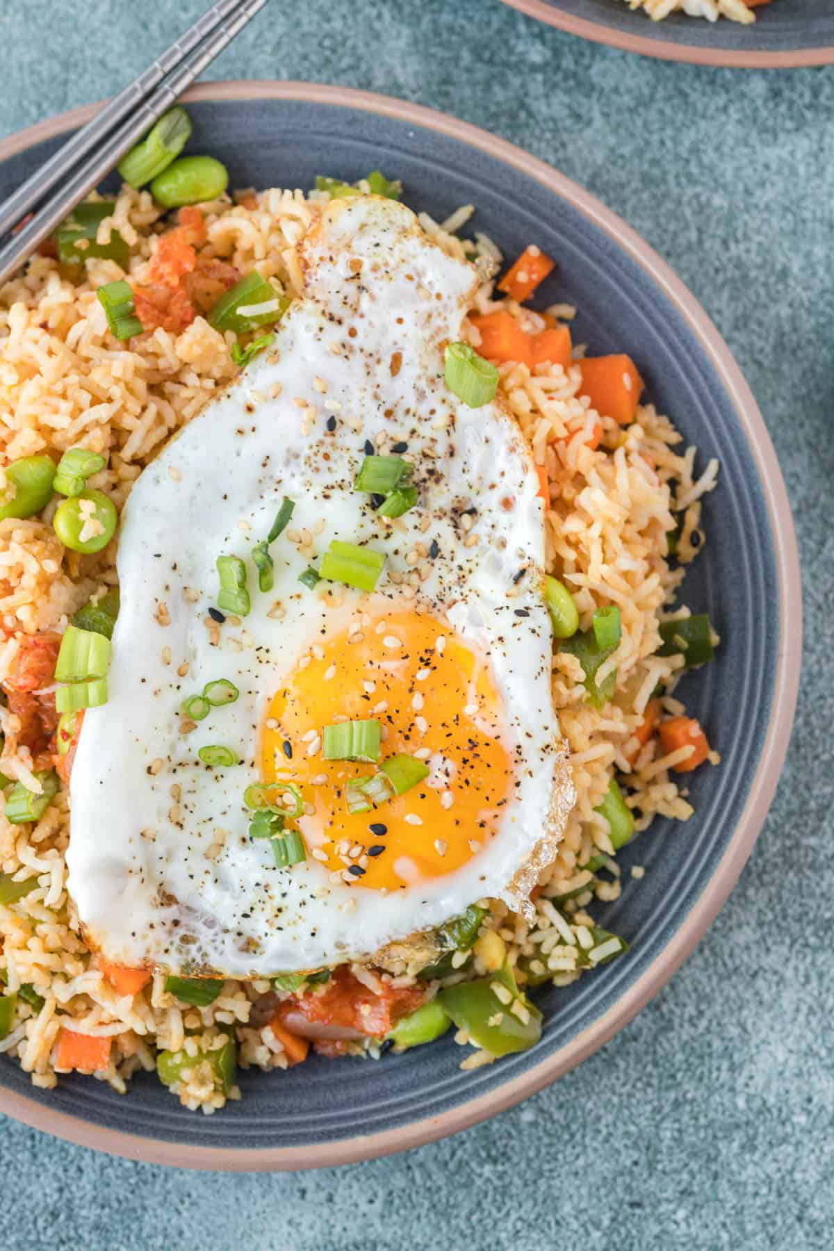 A fried egg is placed on top of a serving of kimchi fried rice.