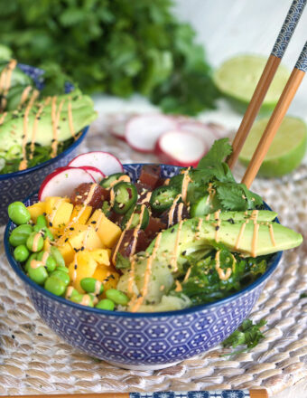 A poke bowl is presented on a round placemat with a pair of chopsticks stuck in it.