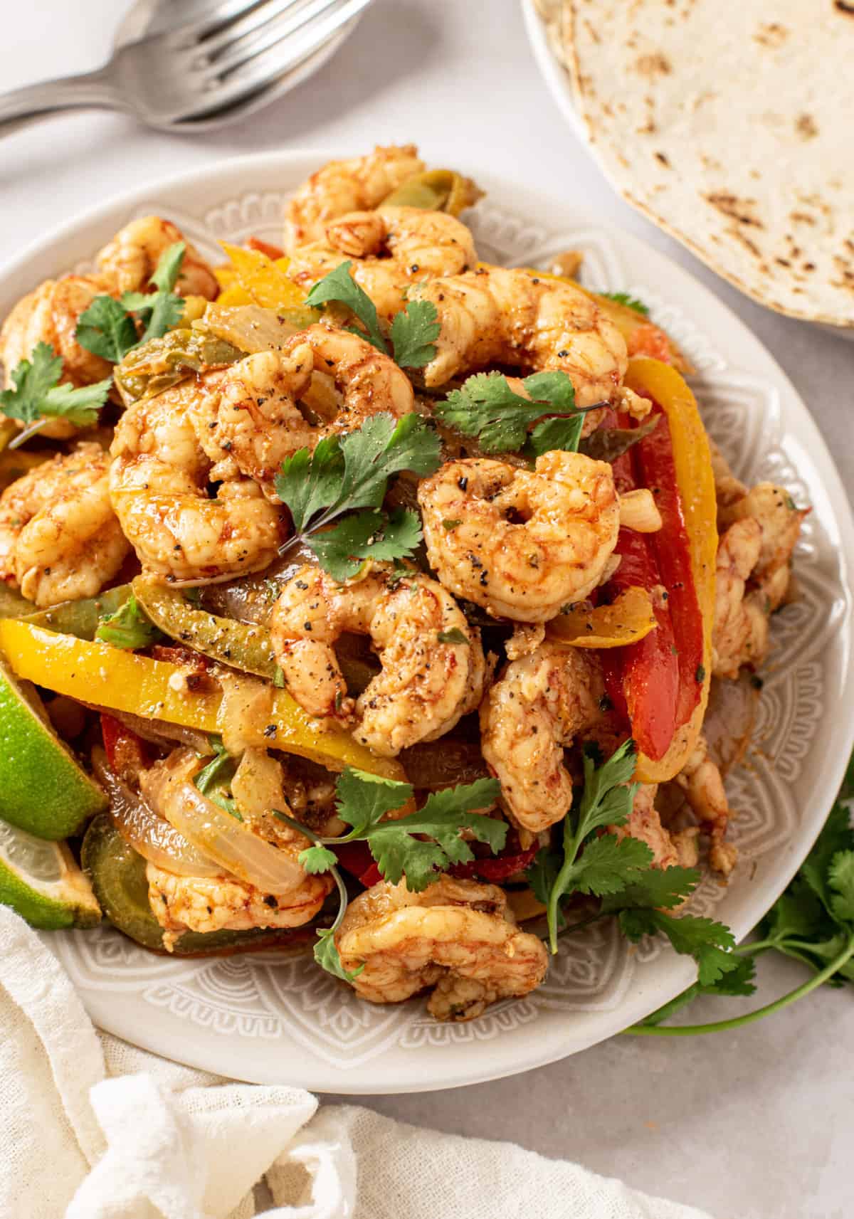 A serving of shrimp fajitas is presented on a round white plate.