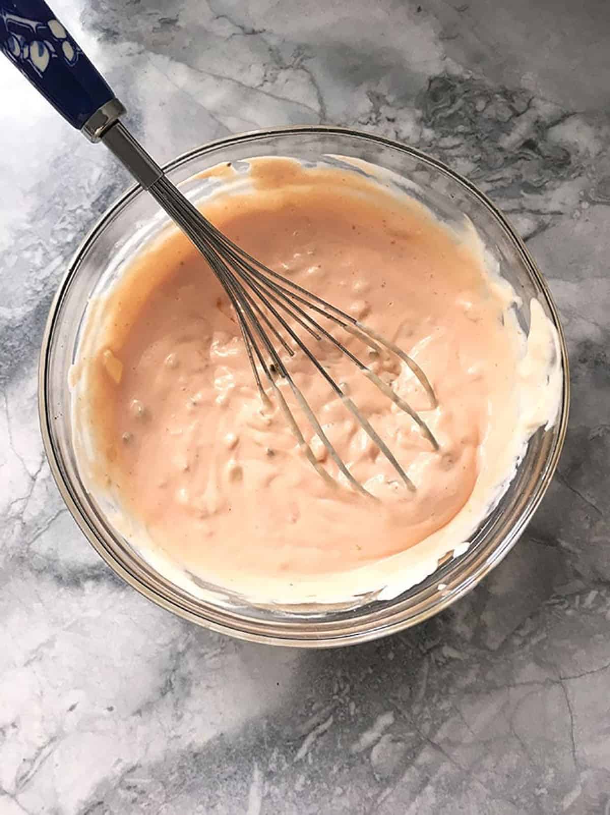Thousand Island Dressing in a glass bowl with a whisk.