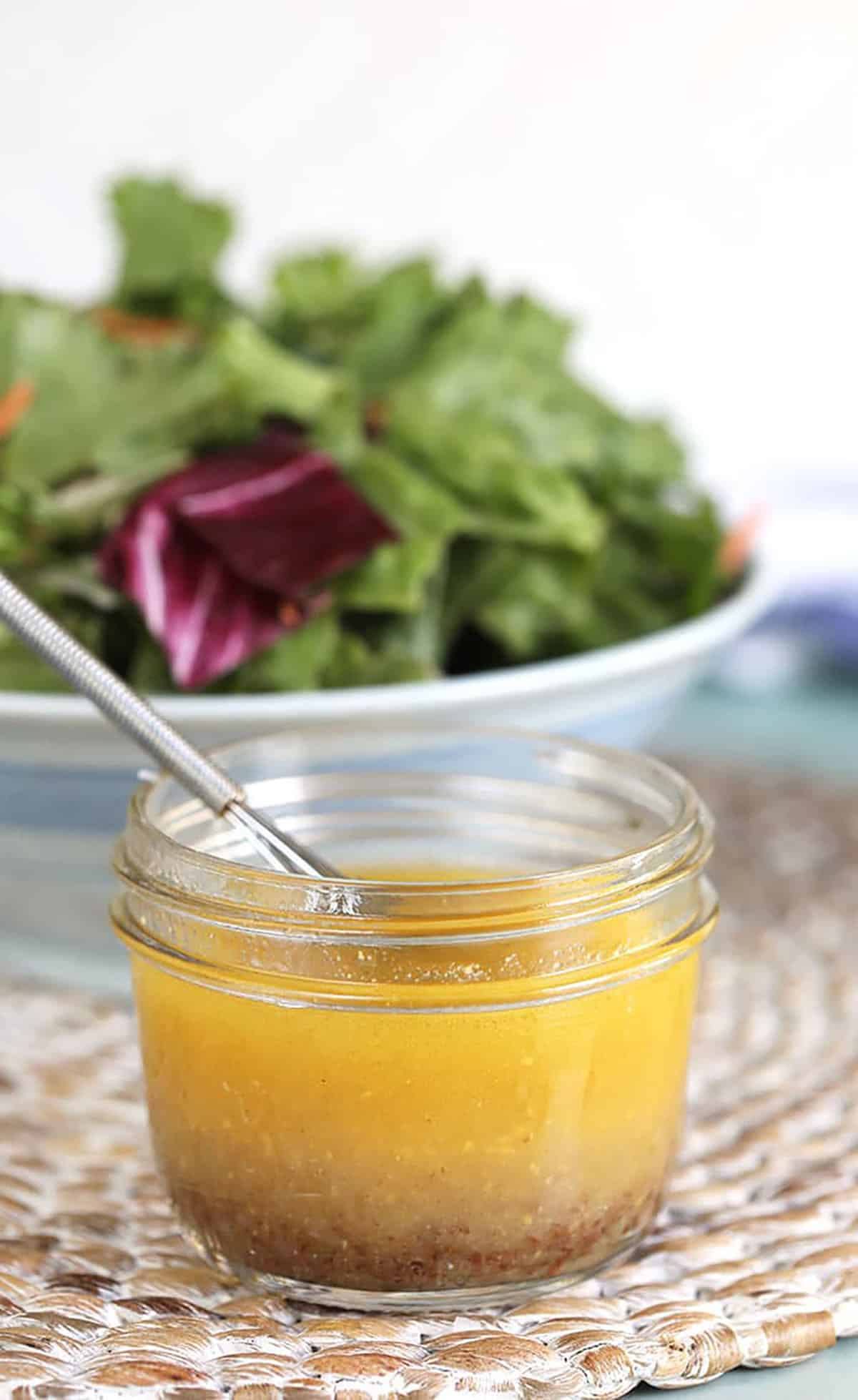 Apple Cider Vinaigrette in a jar with a mini whisk.