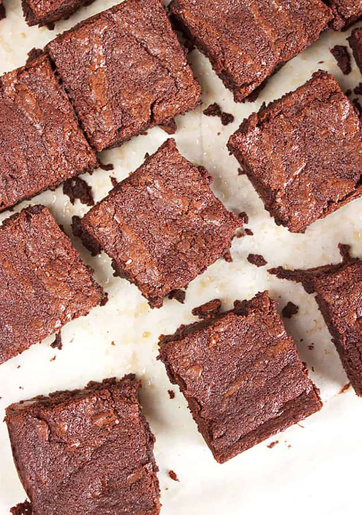 Brownie squares on a piece of parchment paper with brownie crumbs in between the slices.