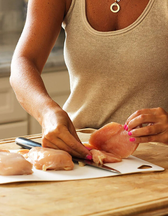 woman opening up a chicken breast that's been sliced in half.