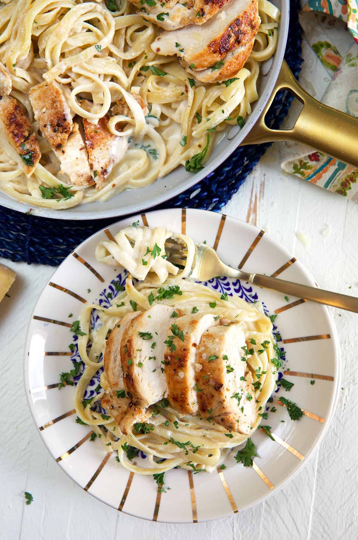A serving of chicken fettucine alfredo is plated next to a full pan.