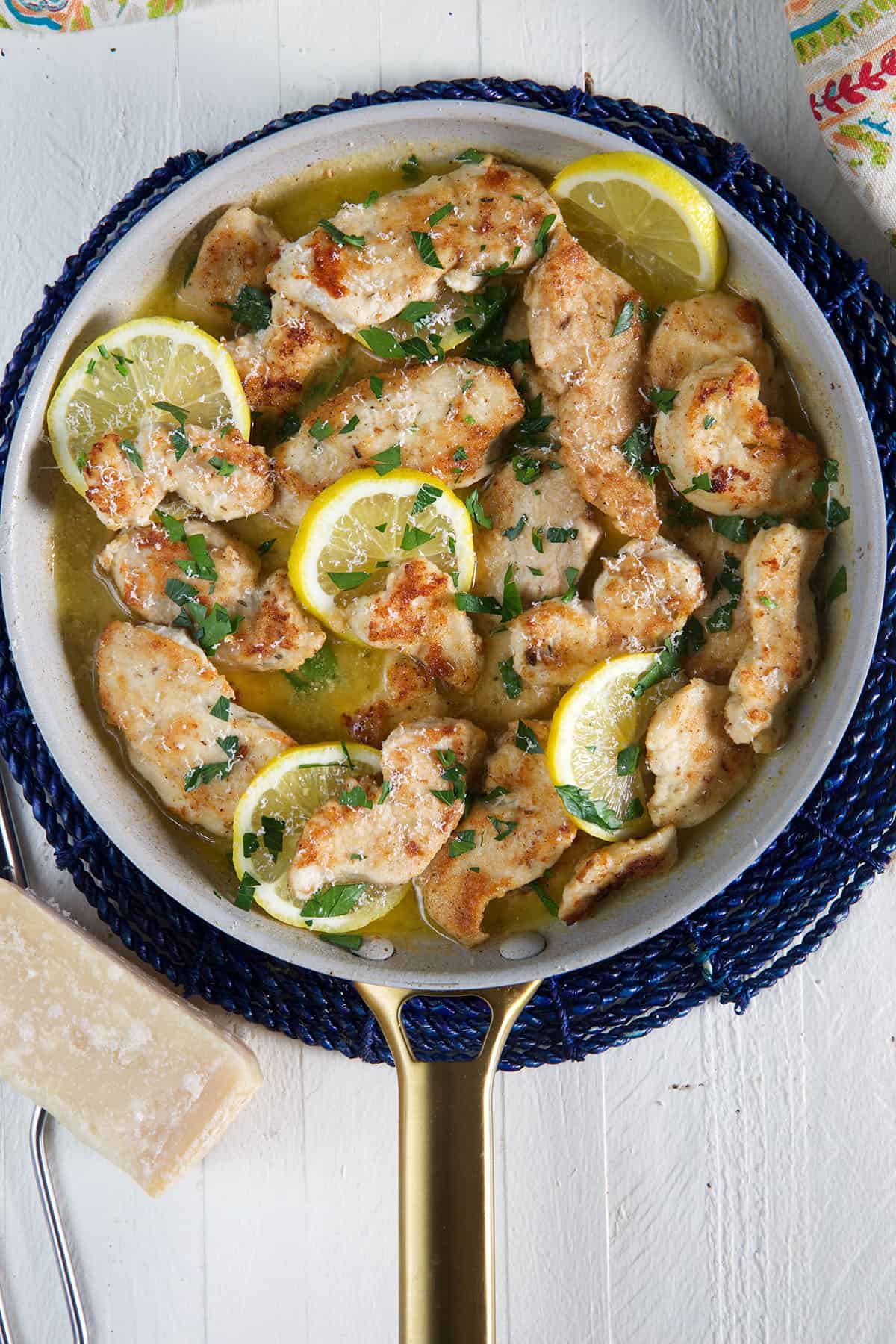 A large pan is filled with cooked chicken and lemon slices.