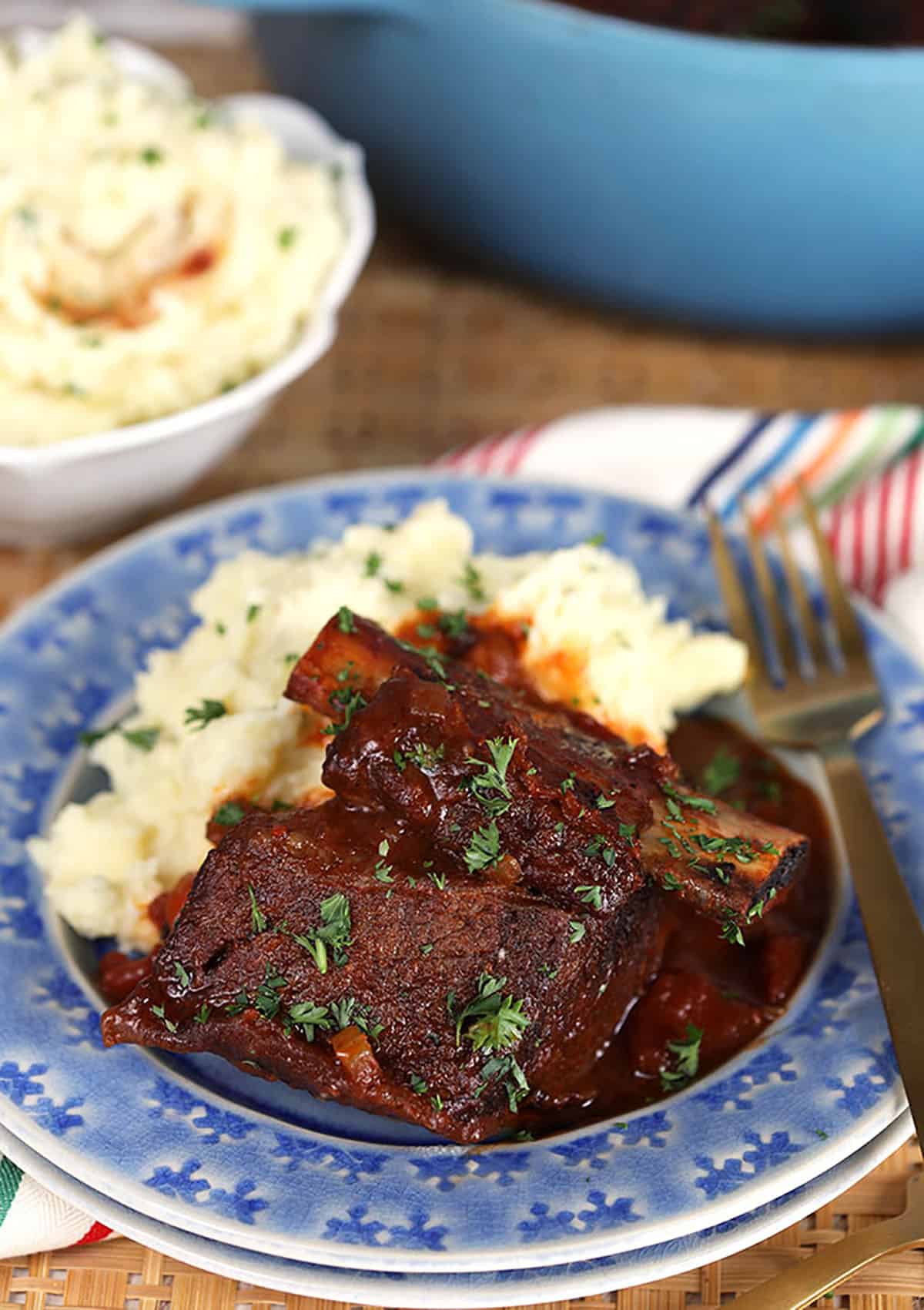 Honey Chipotle Braised Short Ribs and Mashed Potatoes on a blue plate with gold fork.