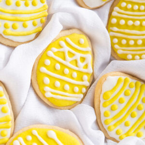 A few yellow and white easter cookies are placed on a gentle white tea towel.