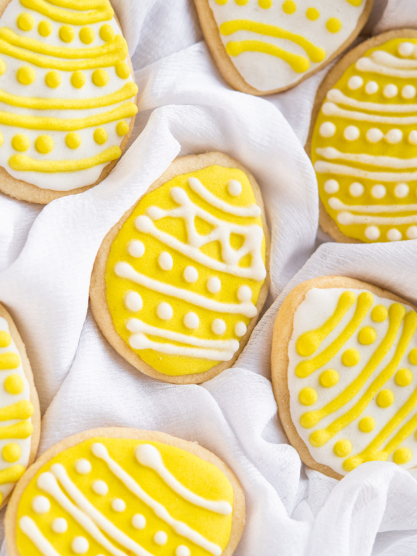 A few yellow and white easter cookies are placed on a gentle white tea towel.