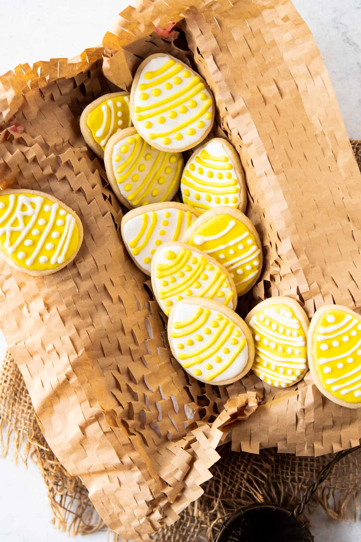 A batch of easter egg sugar cookies are placed in a rectangular basket.