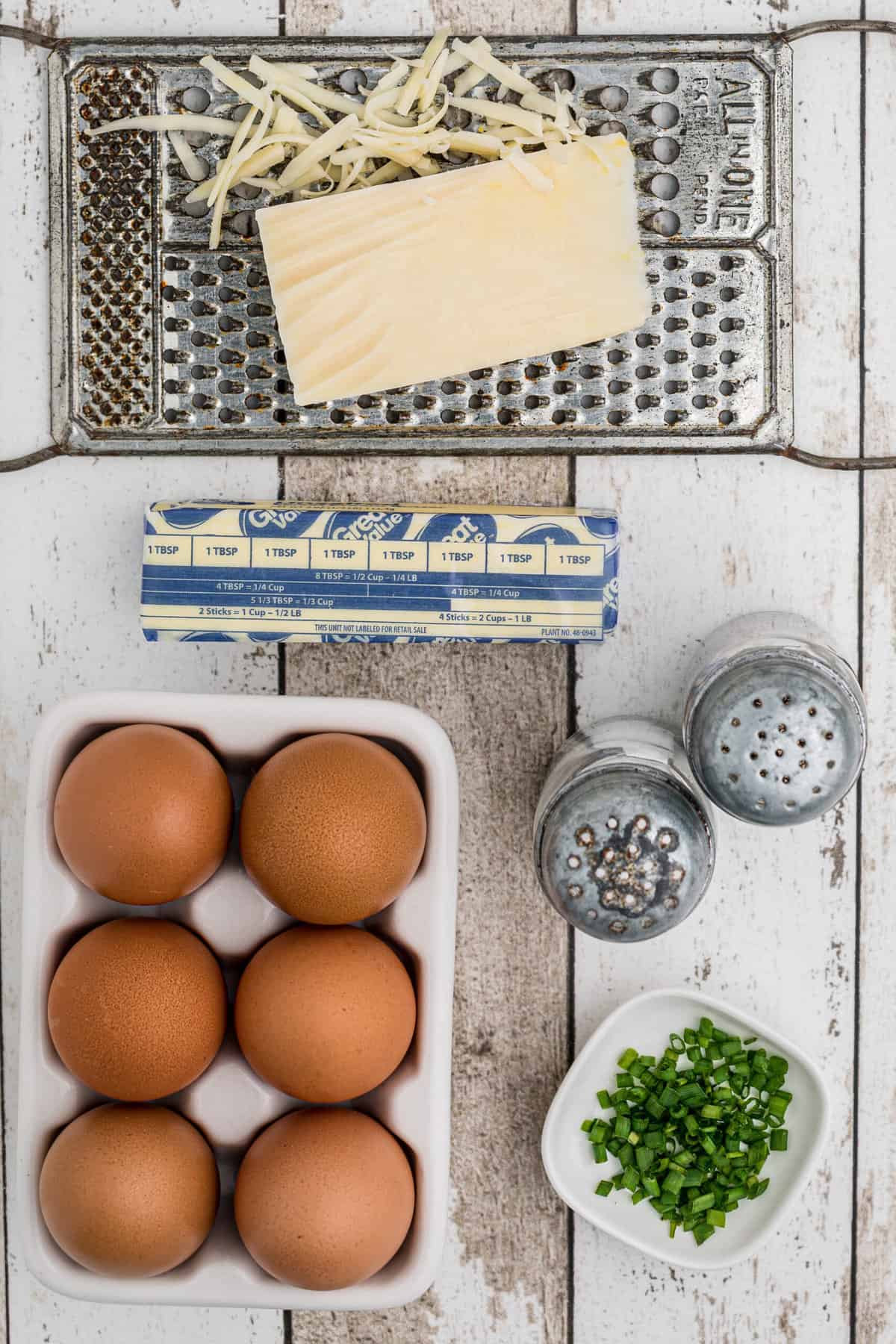 The ingredients for a french omelette are placed on a white wooden surface.
