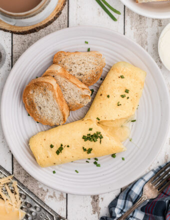 A french omelette is plated with three pieces of crostini.