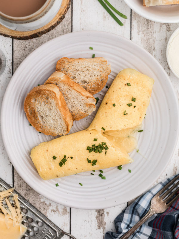 A french omelette is plated with three pieces of crostini.