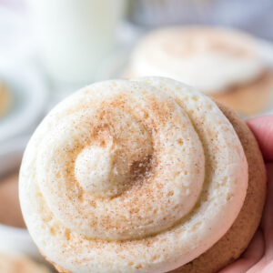 A snickerdoodle cookie has been frosted and dusted with cinnamon sugar powder.