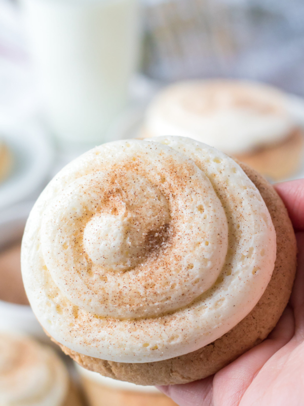 A snickerdoodle cookie has been frosted and dusted with cinnamon sugar powder.