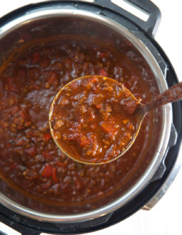 A ladel is scooping out a serving of chili from the Instant Pot.