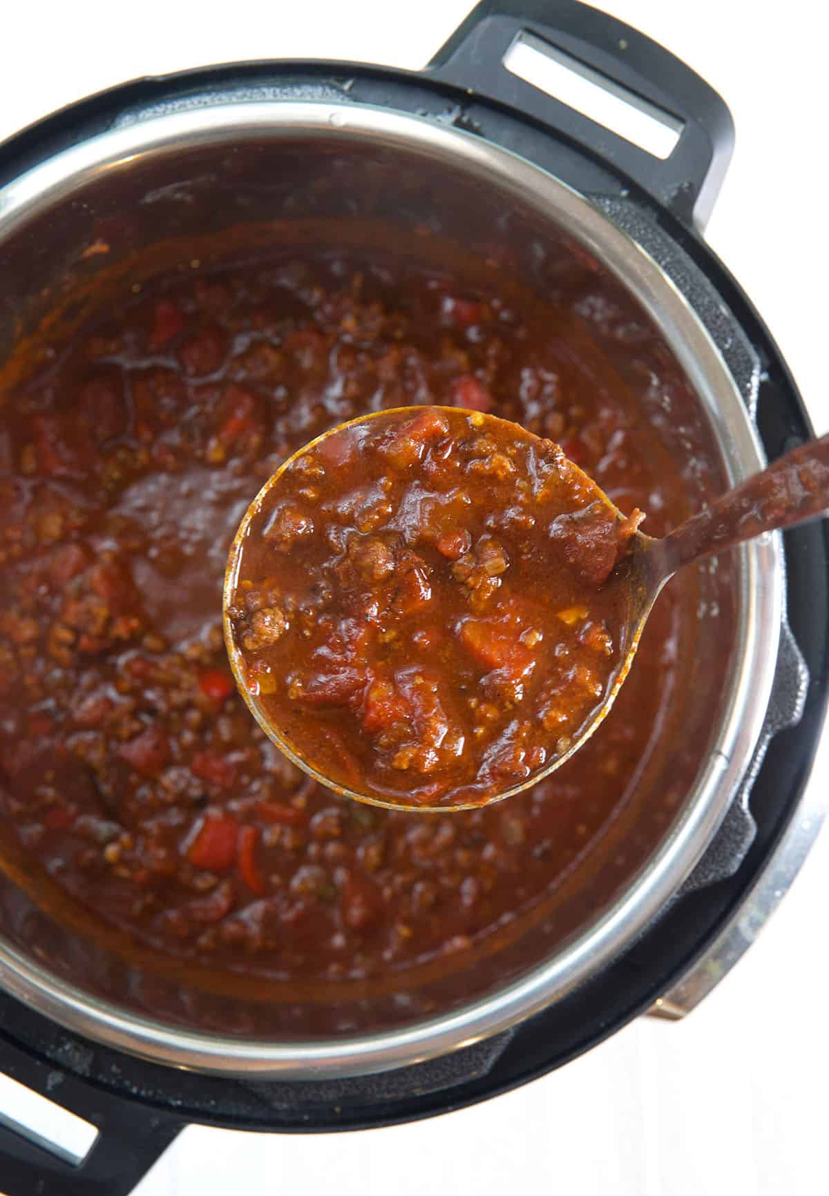 A ladel is scooping out a serving of chili from the Instant Pot.